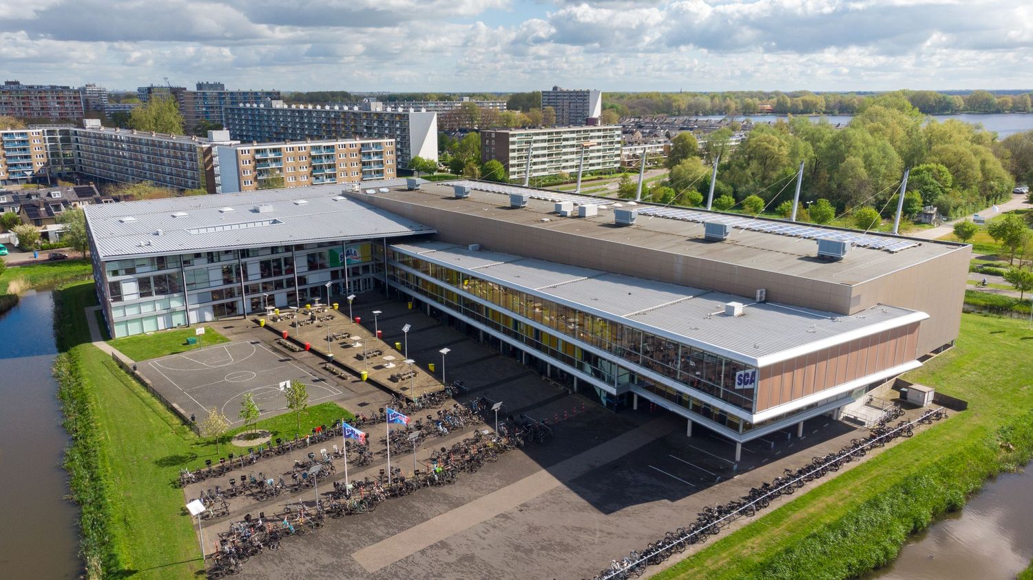 Dronefoto van het Scala College Nieuwe Sloot in Alphen aan den Rijn, moderne schoolarchitectuur aan het water.