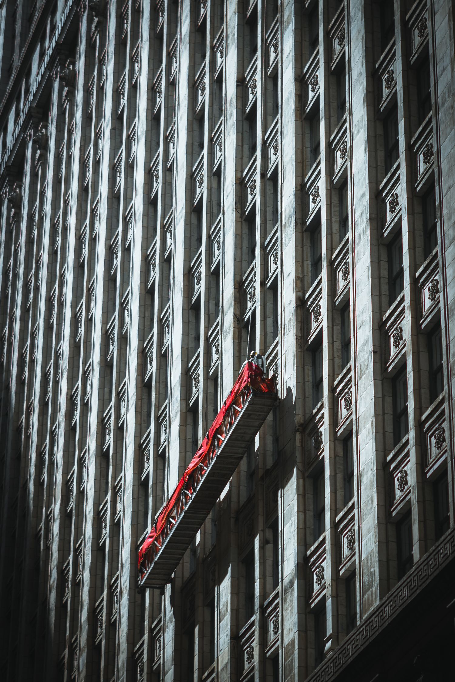 Architectuurfoto in Chicago van gevel met repeterende ramen en een glazenwassersplatform met rode accenten.