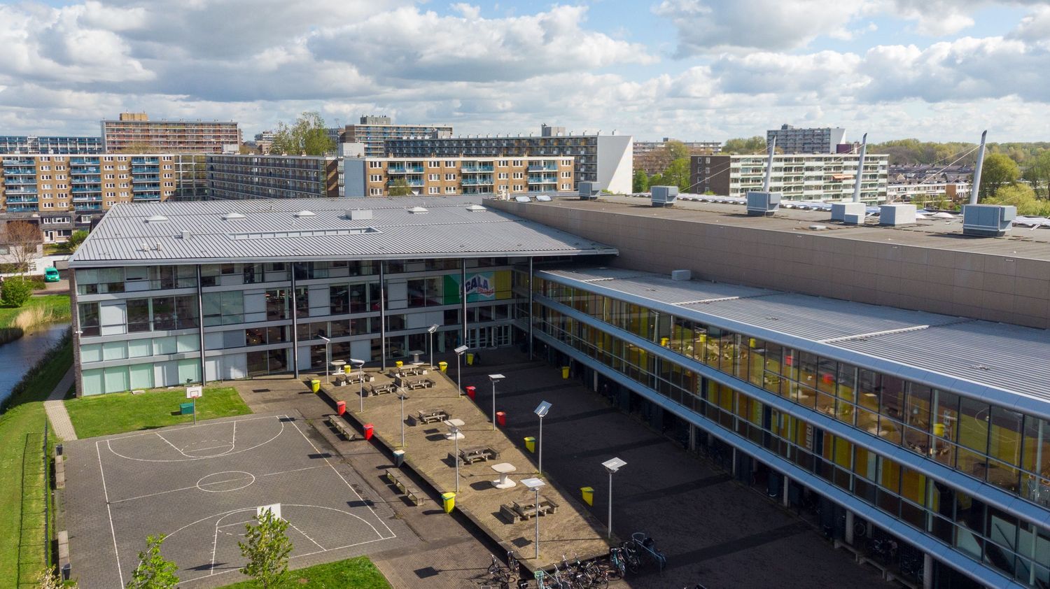 Dronefoto van het Scala College Nieuwe Sloot in Alphen aan den Rijn, moderne schoolarchitectuur aan het water.