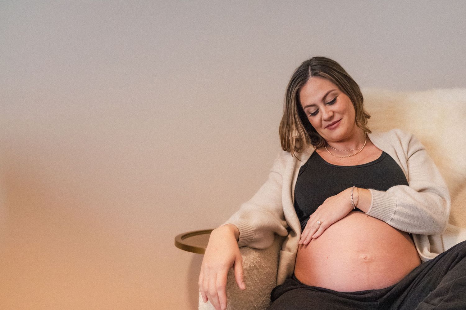 Pregnant momma rests hand on her belly in nursery during at-home maternity photography session in Austin, Texas
