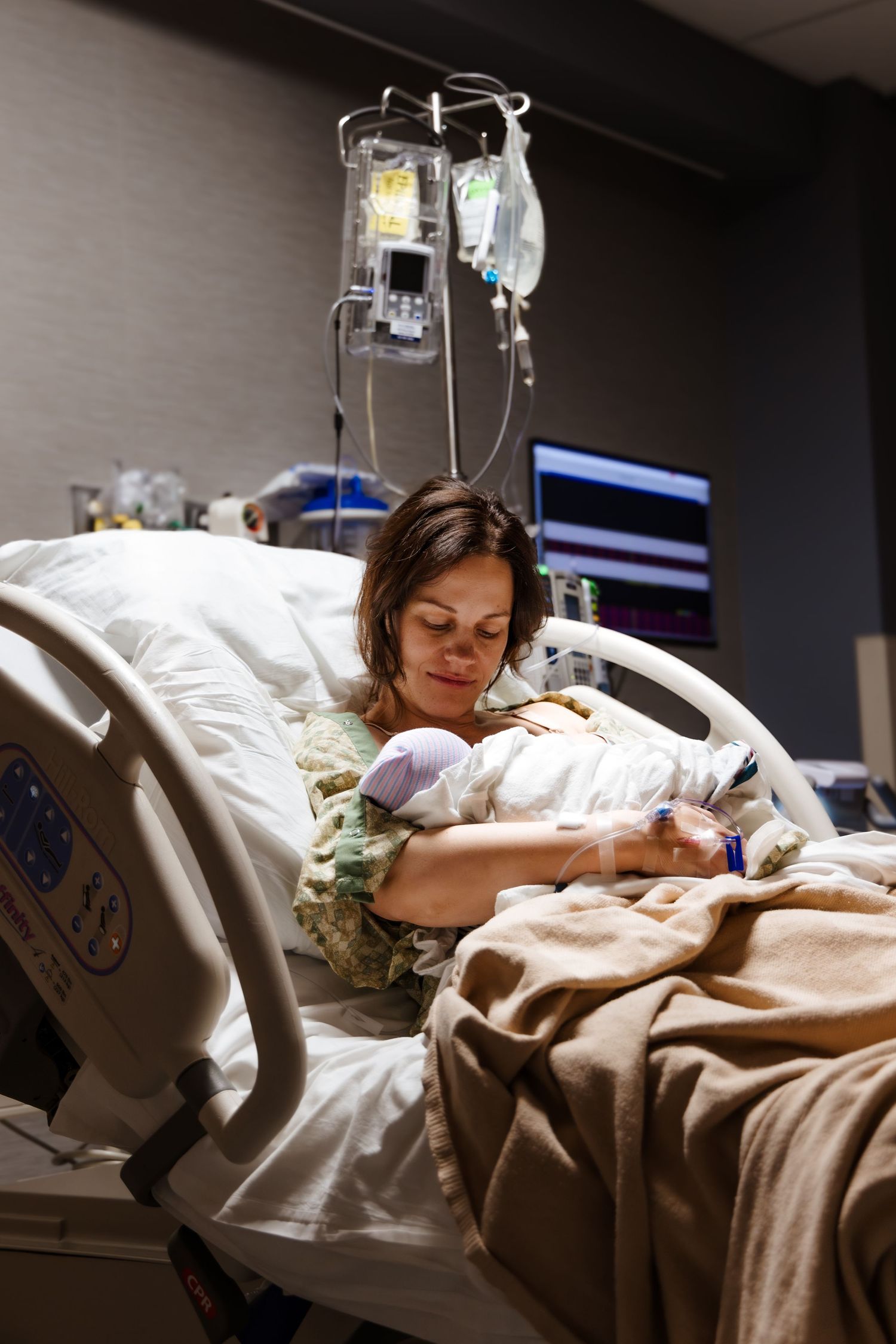 Mother lovingly gazes down at newborn baby in hospital bed, post-birth.