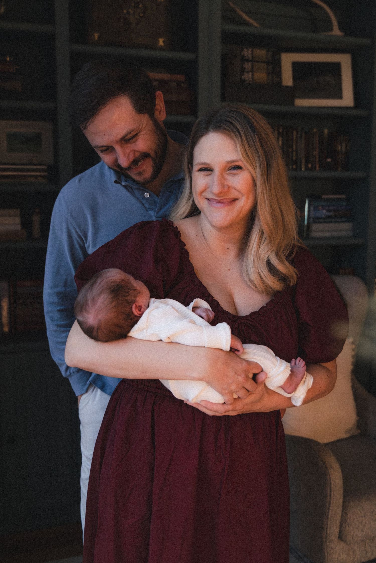Dad looks at newborn baby while mom holds her during holiday newborn session