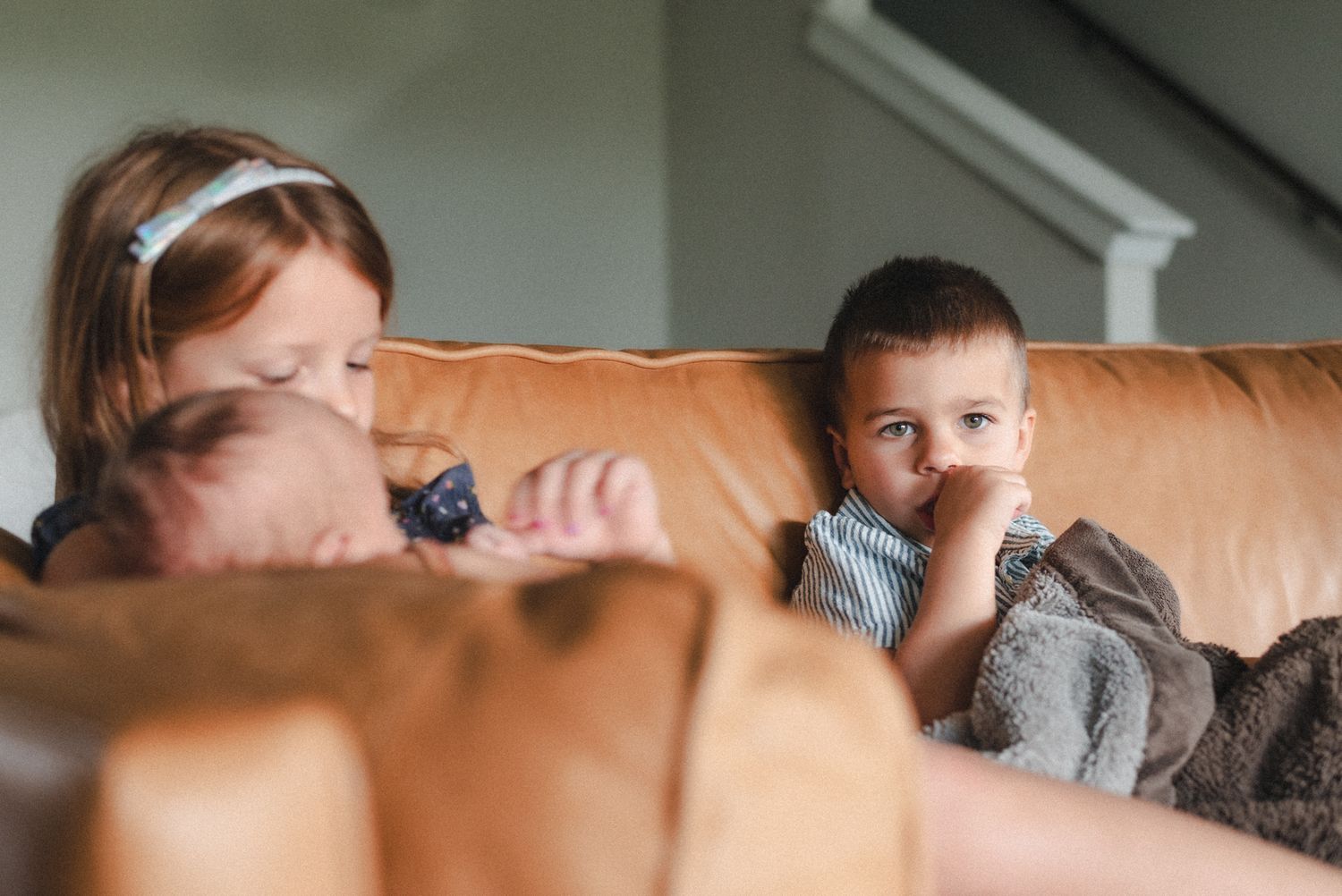 Boy sucks his thumb looking at the camera during at-home family session