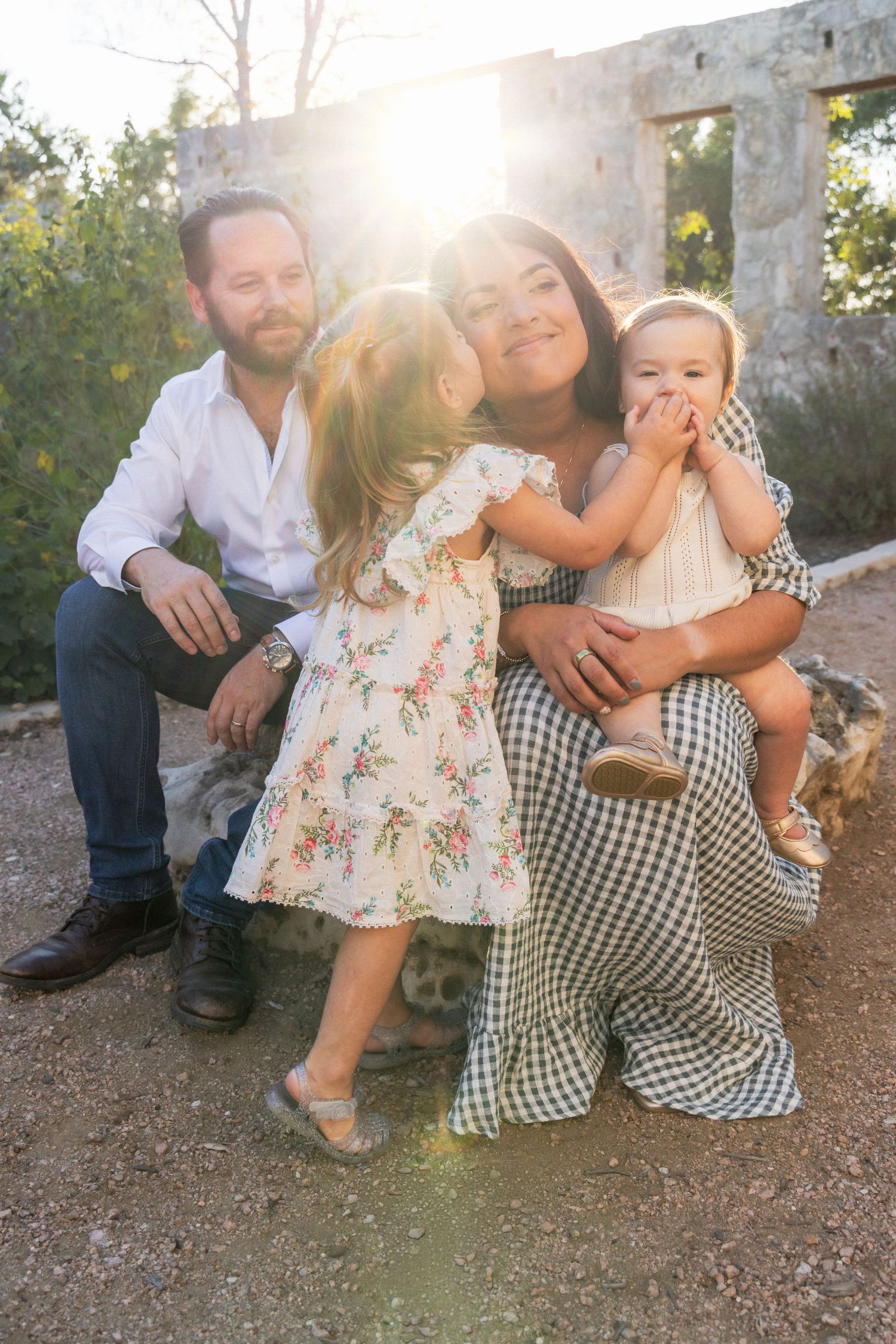 Daughter kisses mom on cheek during outdoor family photography session