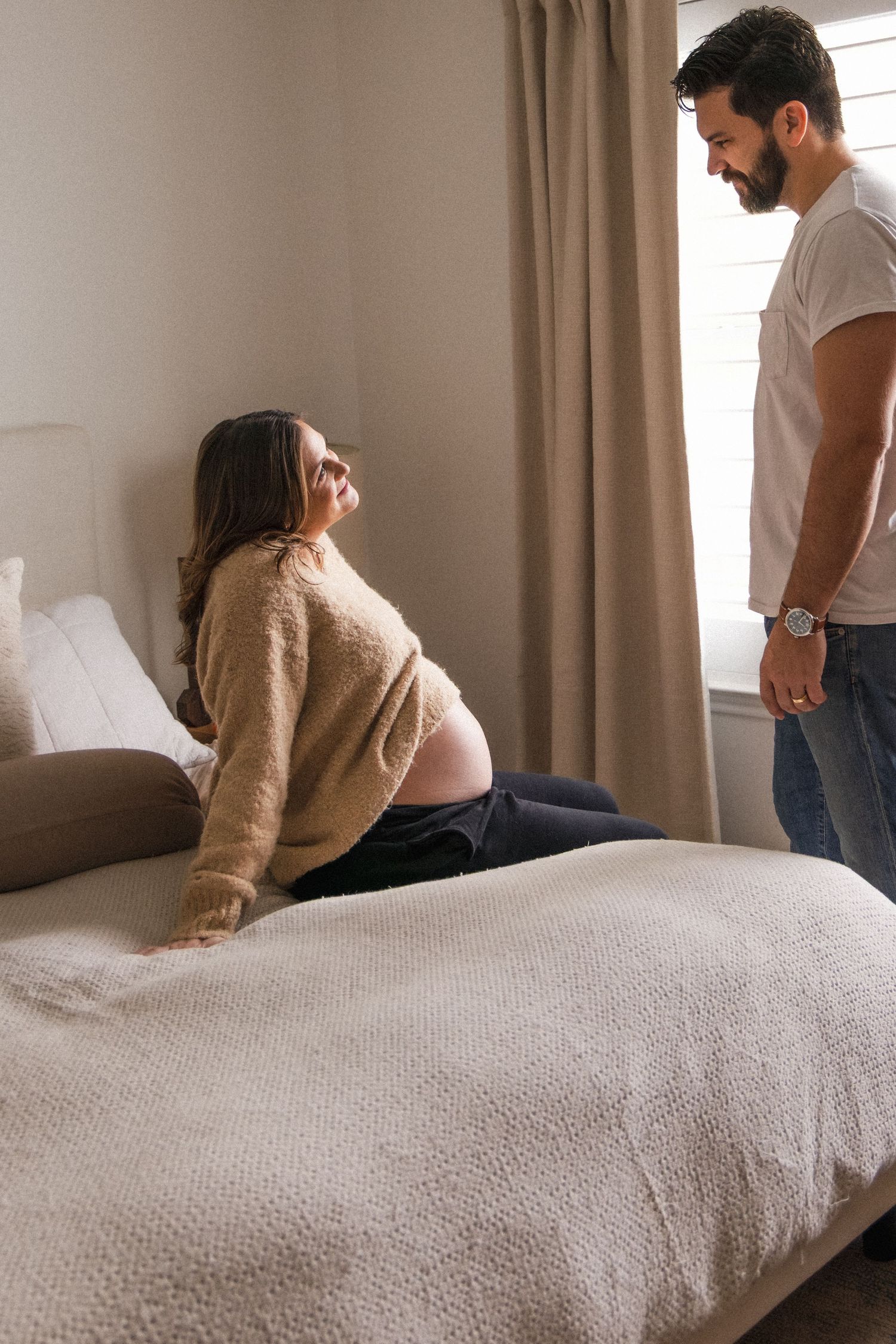 Pregnant woman looks up at husband during at-home maternity photography session