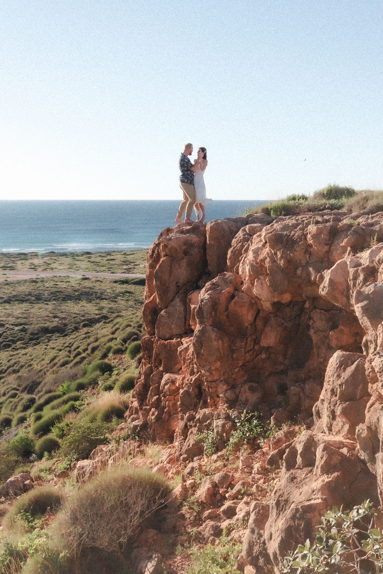 Couple dances on cliffs overlooking the ocean before sunset elopement wedding ceremony