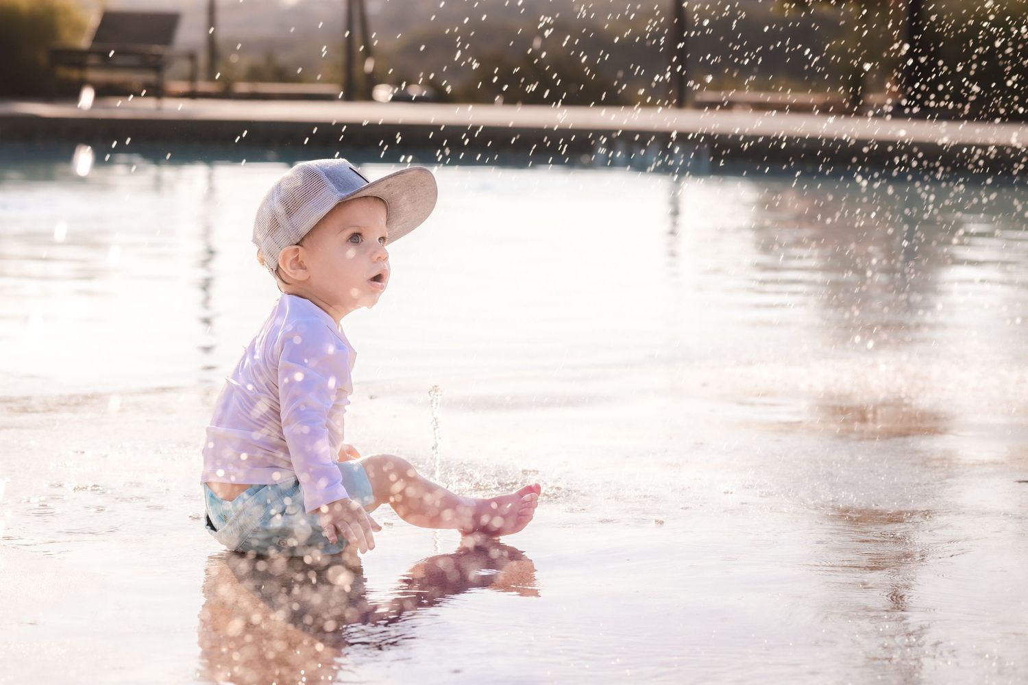 Child plays in splash pad at pool during first birthday photoshoot