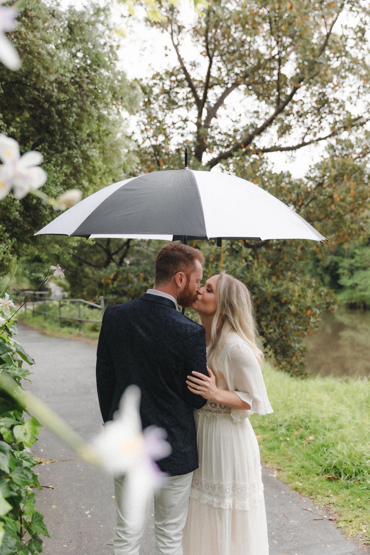 Couple kisses under umbrella on rainy engagement session