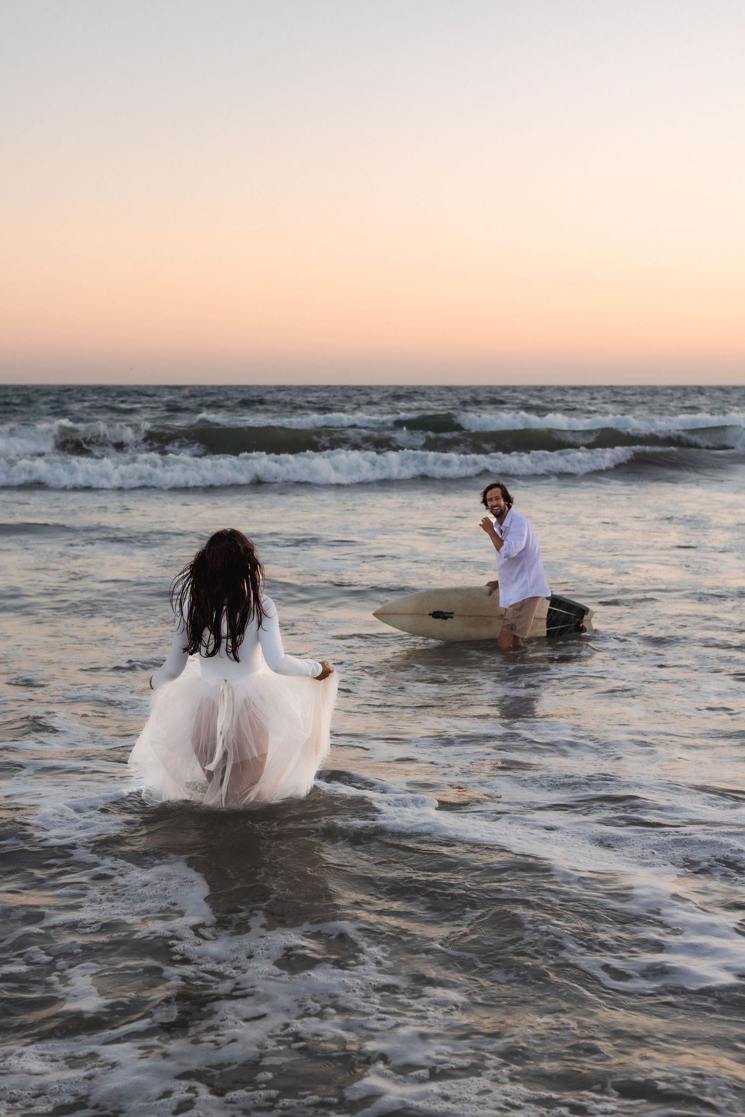 surfing couple running into the ocean during trash the dress beach session
