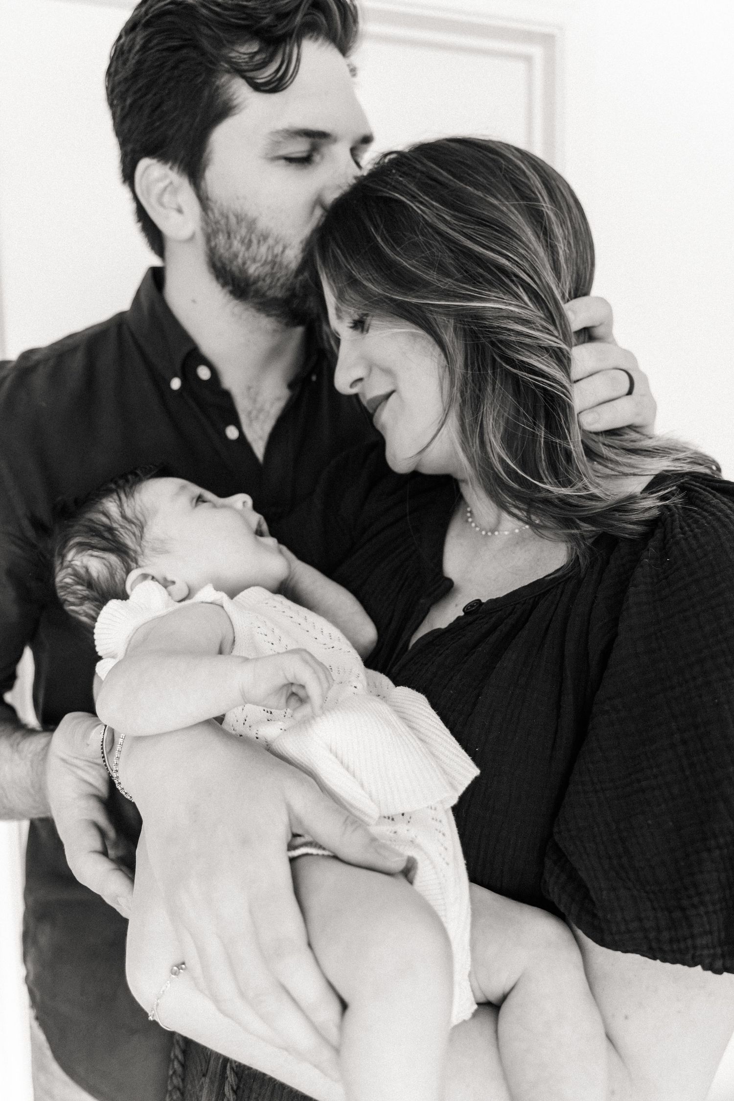 Father and mother holding new baby in their arms while standing