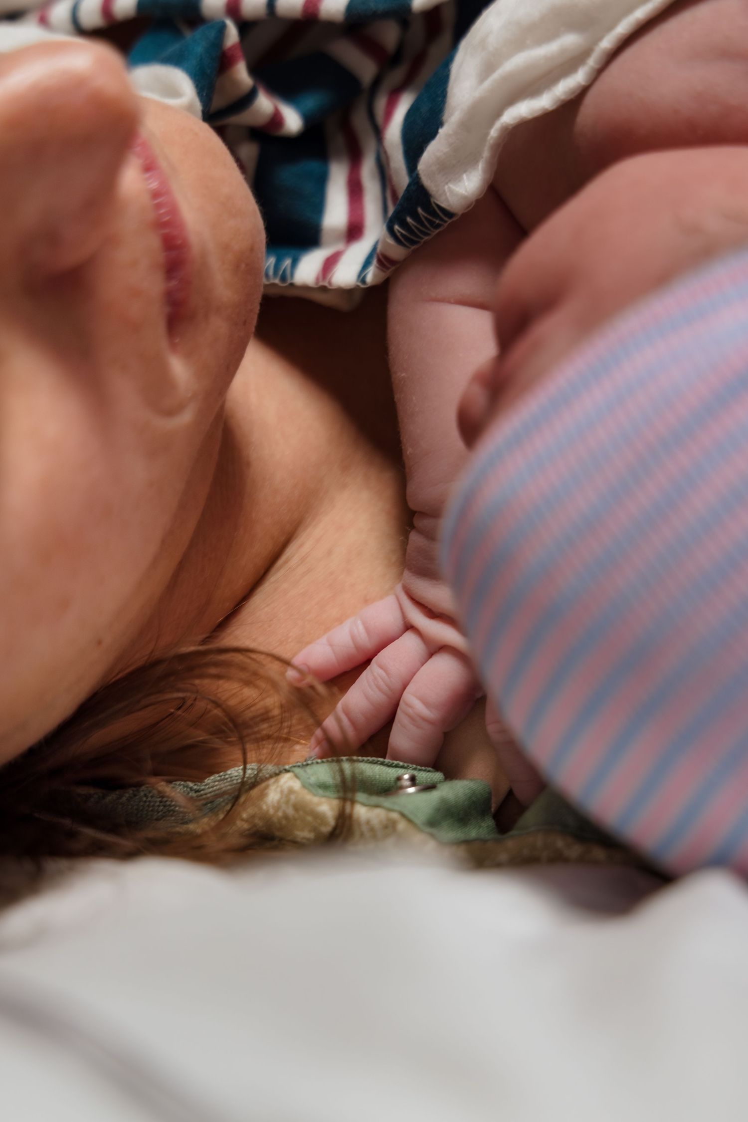 Newborn baby puts her hand on her mom moments after hospital birth.