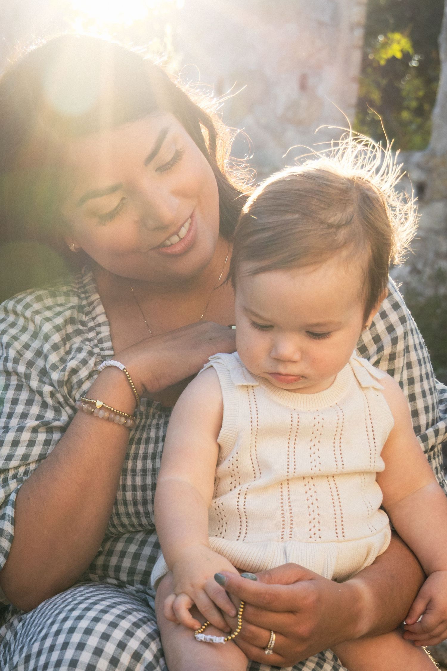 Mom holds young child on lap during sunset family photography session