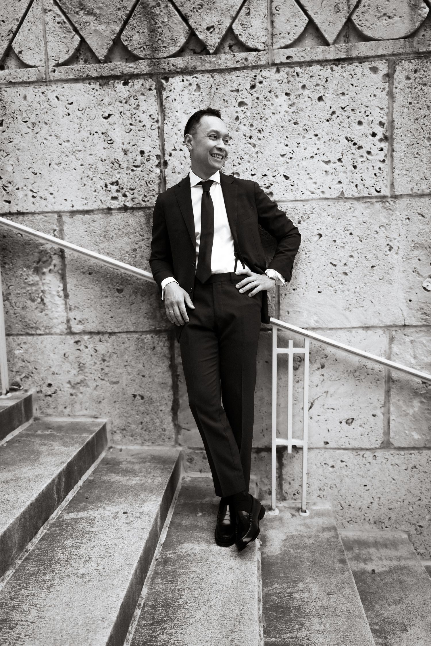 Black and white edit of groom portrait on limestone stairs in Austin Texas