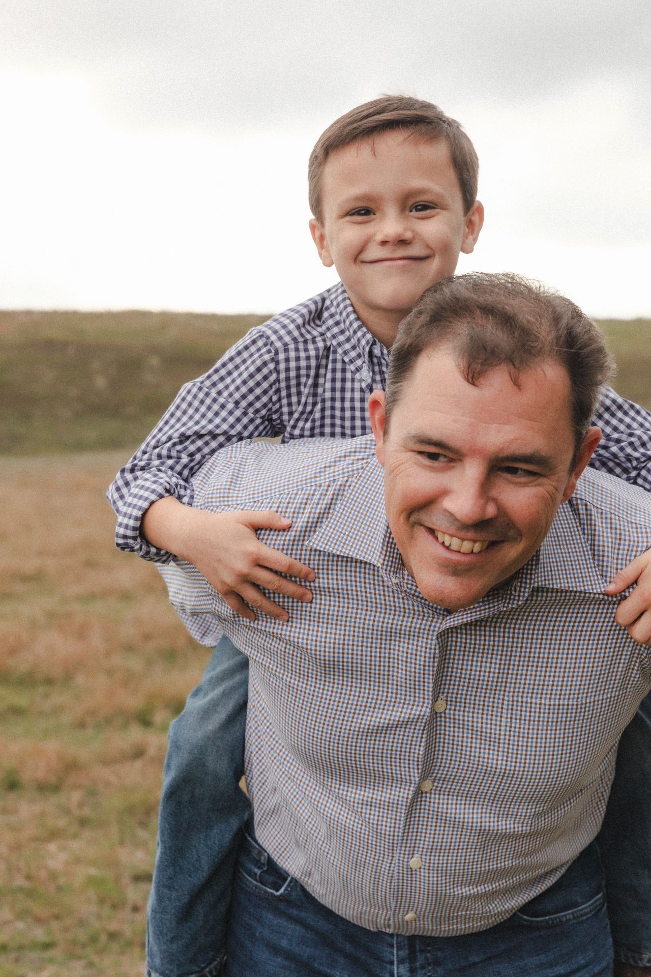 Father gives his son a piggyback ride during during family photoshoot
