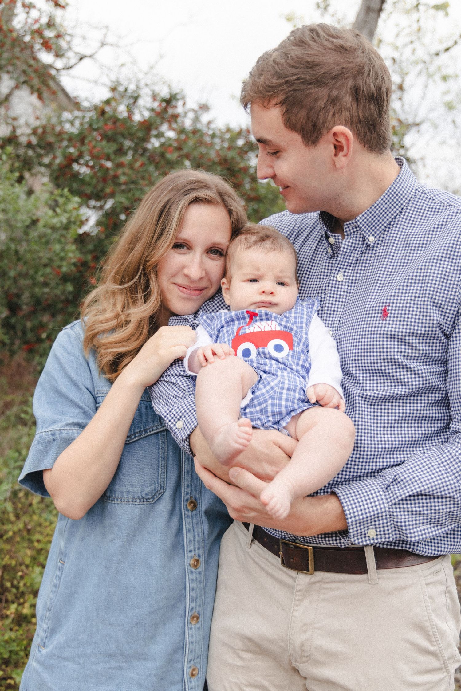 Couple wearing blue holds young infant during outdoor family photography session