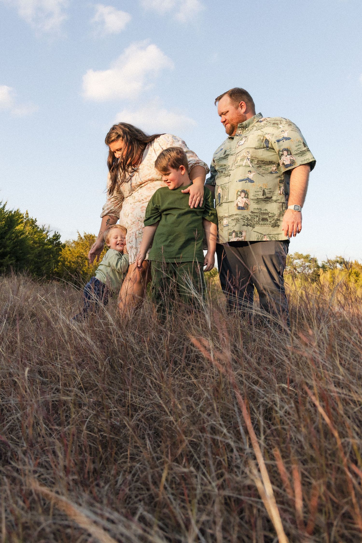Family with two young sons plays together in the tall grass during family photography session