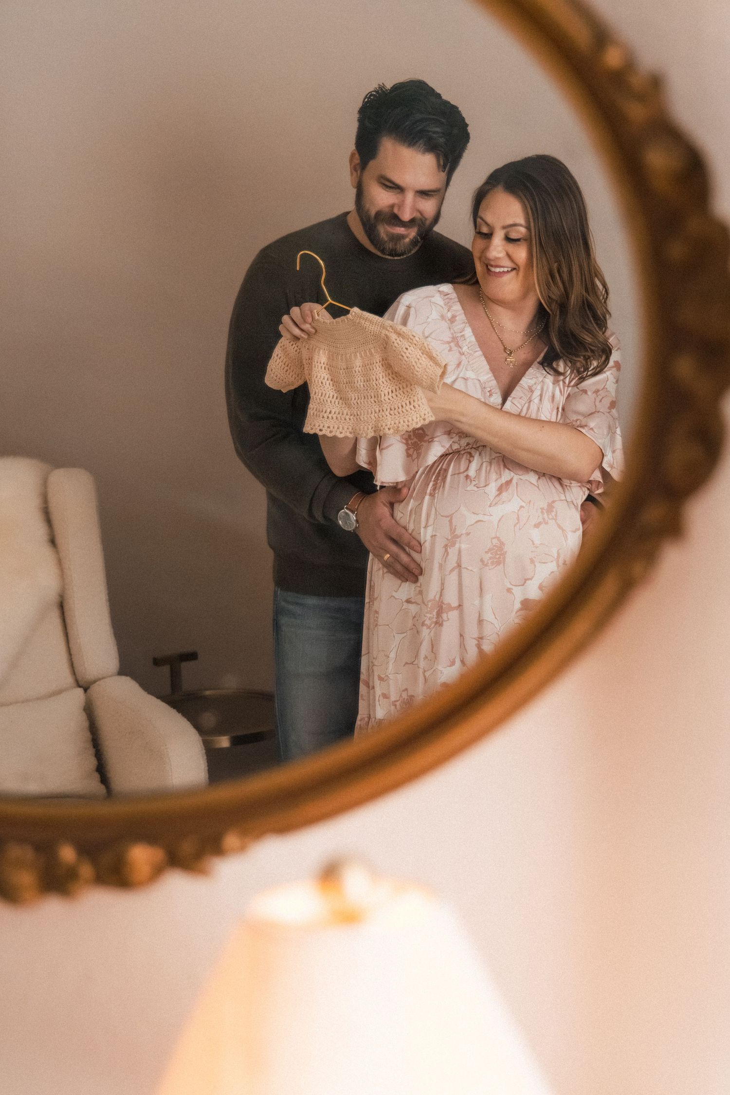 Couple looks at heirloom outfit for baby during at-home maternity session
