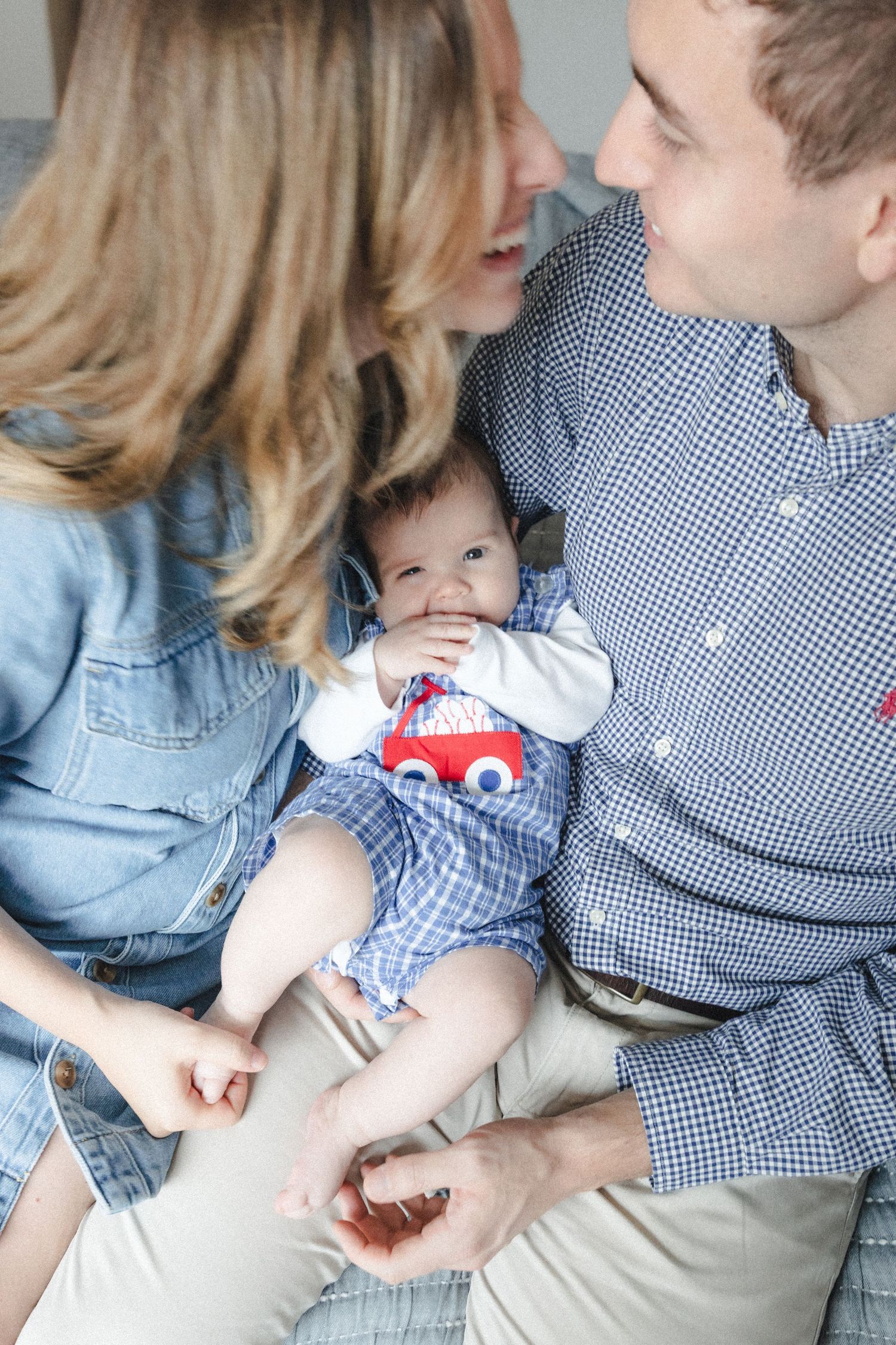 Couple leans in while holding young infant during in-home family photography session