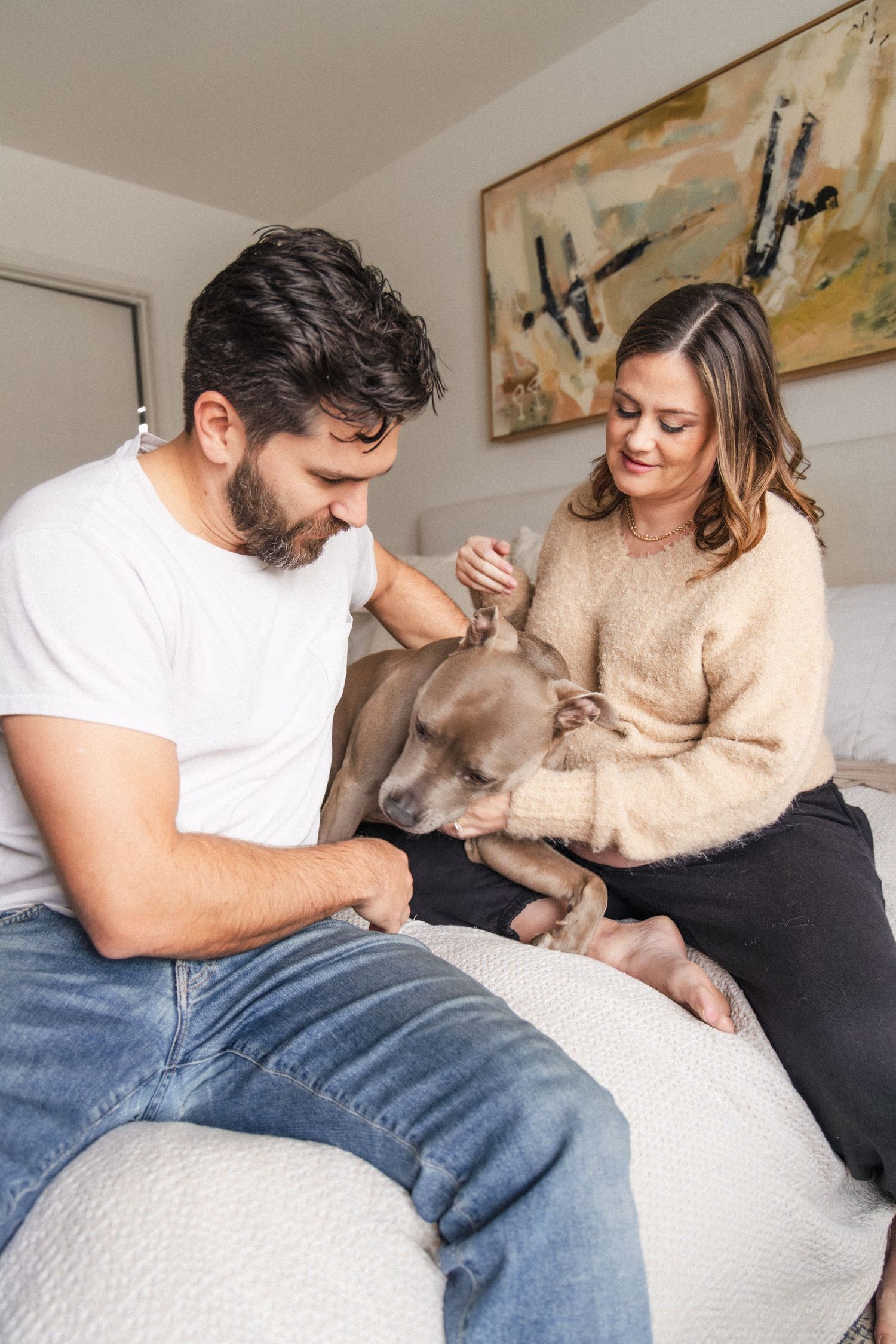 Couple plays with their god on the bed during at-home maternity photography session