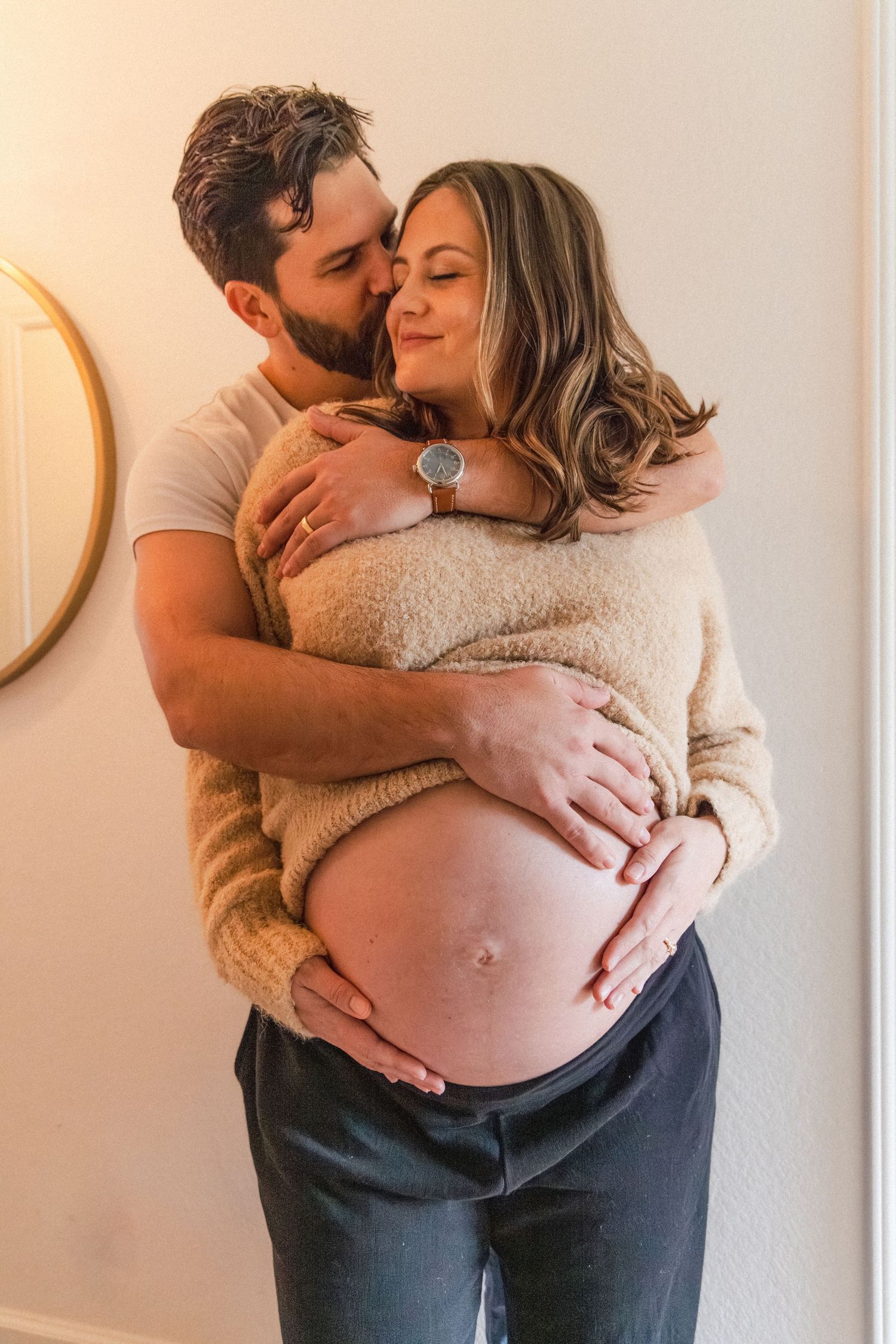 Handsome couple romantically embraces during at-home maternity photography session