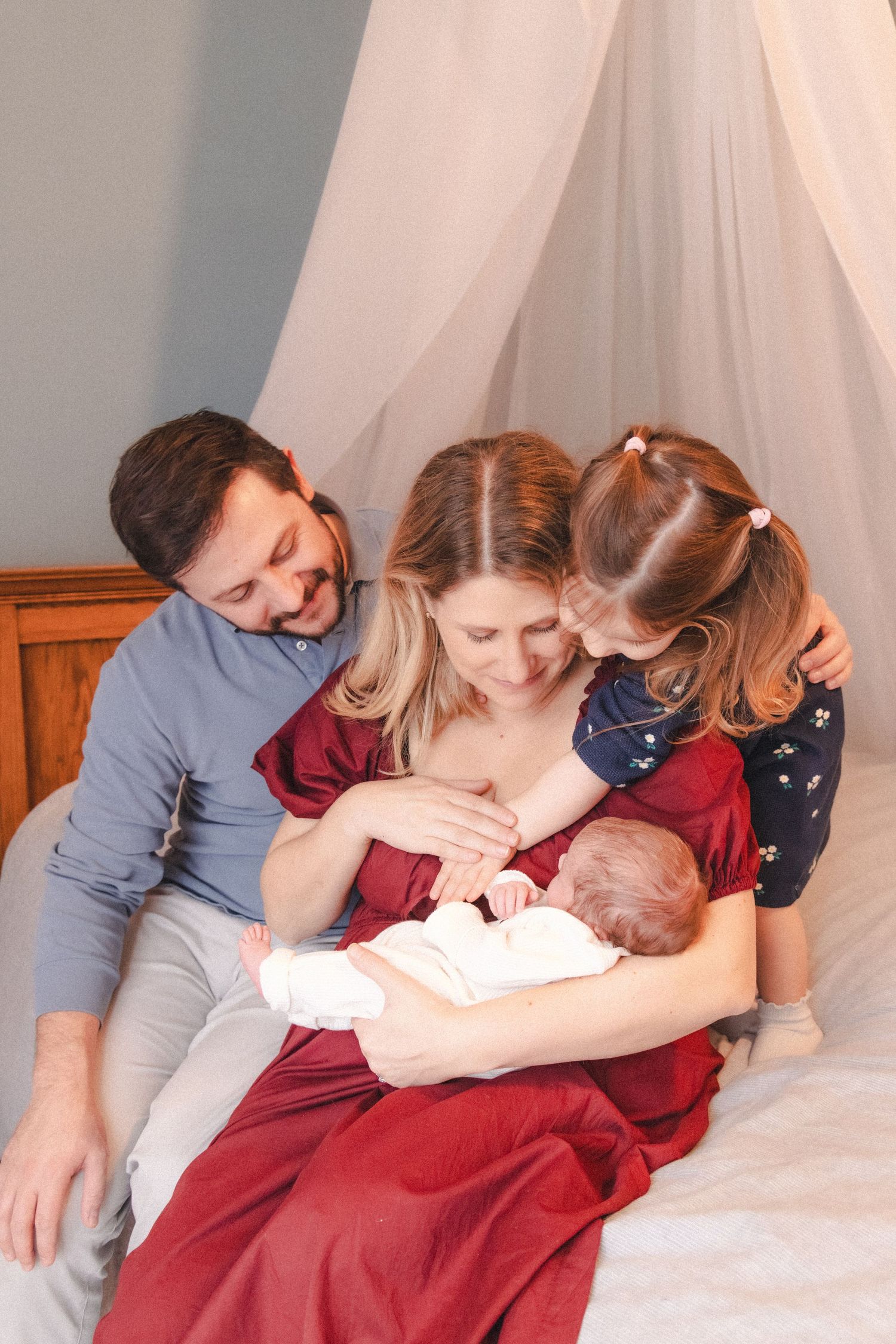 Family embraces on bed during newborn family photography session