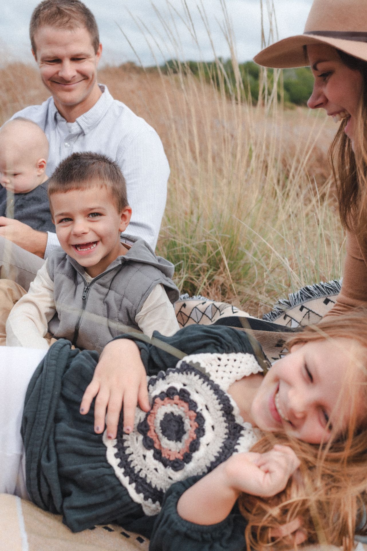 Family plays on blanket in the grass in the Texas Hill Country during a ranch family photo session