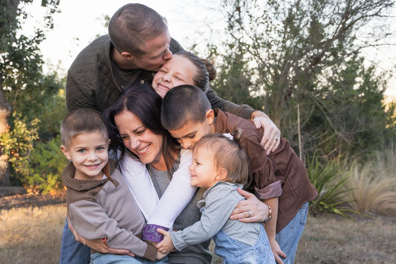Family gives bear hugs during outdoor family photo session in the Texas Hill Country