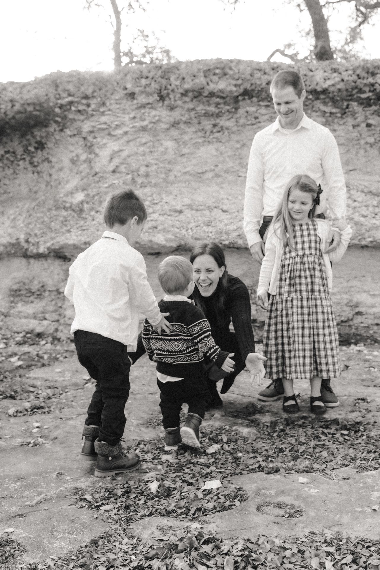 Mom crouching down with children running into her arms during outdoor family photography session