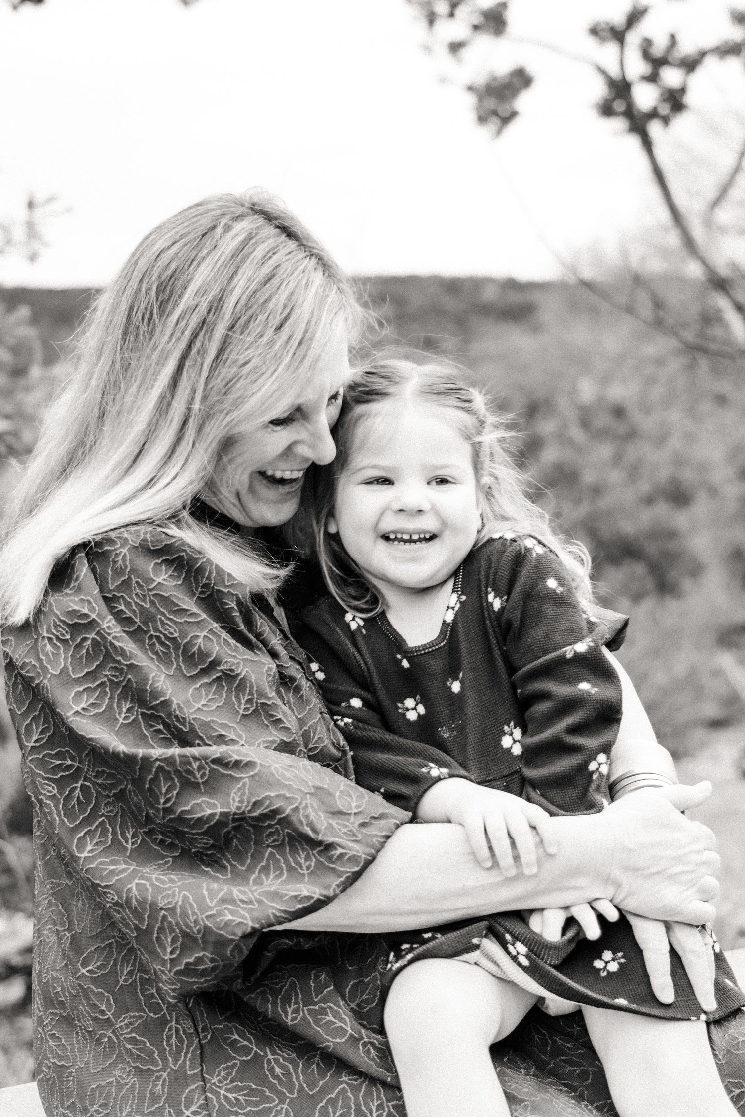 Grandma plays with granddaughter on lap during outdoor extended family photography session