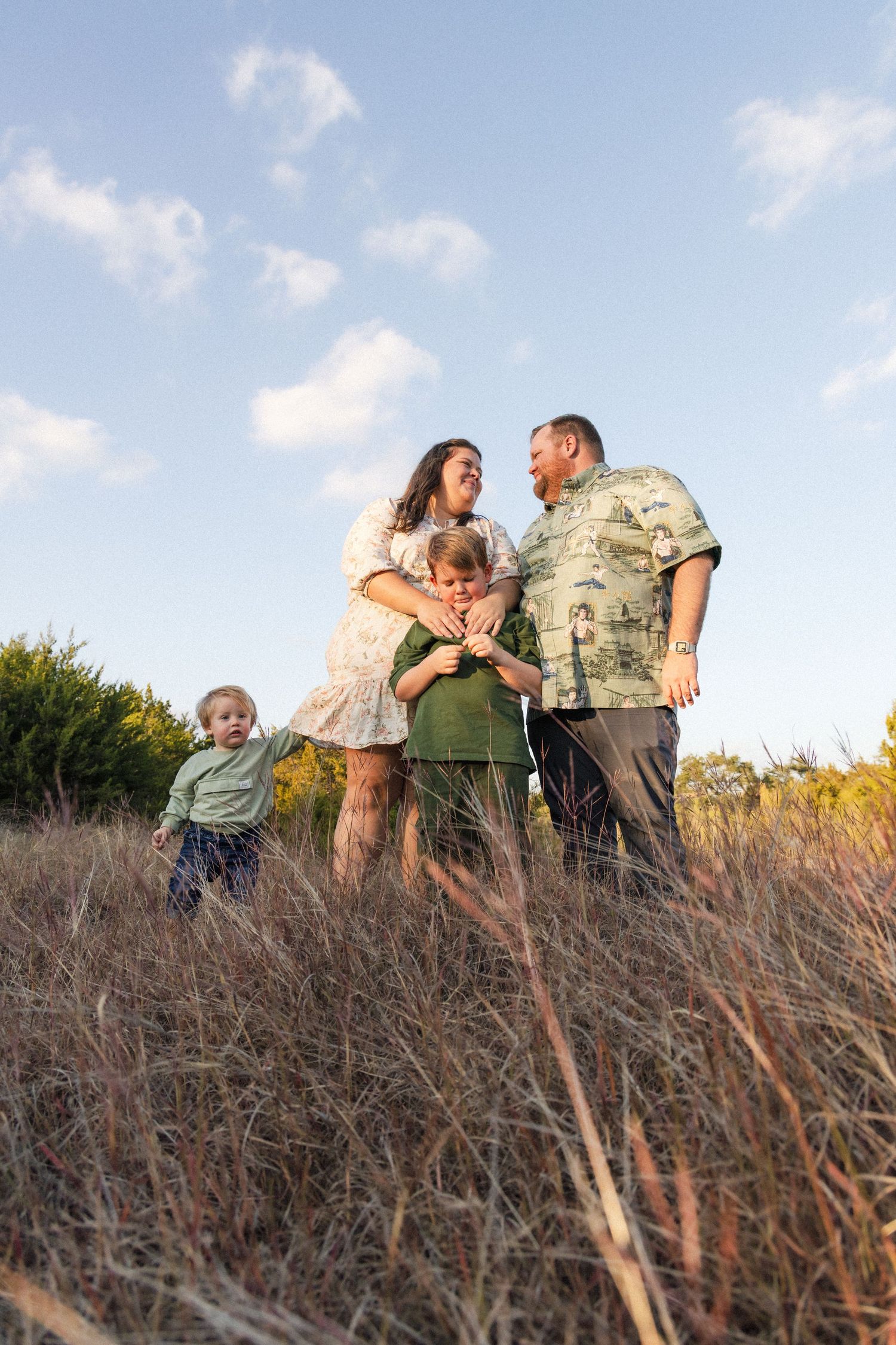 Family standing in tall grass field during outdoor family photo session