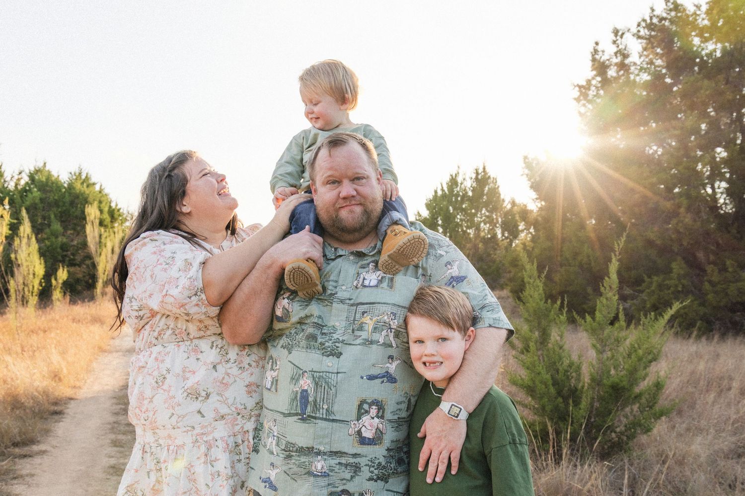 Mom looks up at son on dad's shoulders during sunset family photography session in the Texas Hill Country