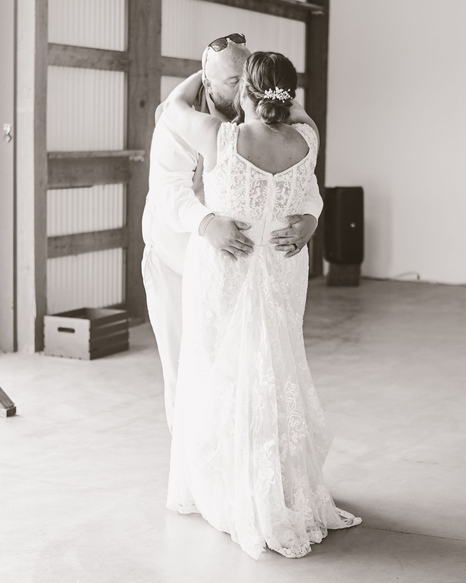 A bride in a lace wedding gown is photographed in a bright indoor space.