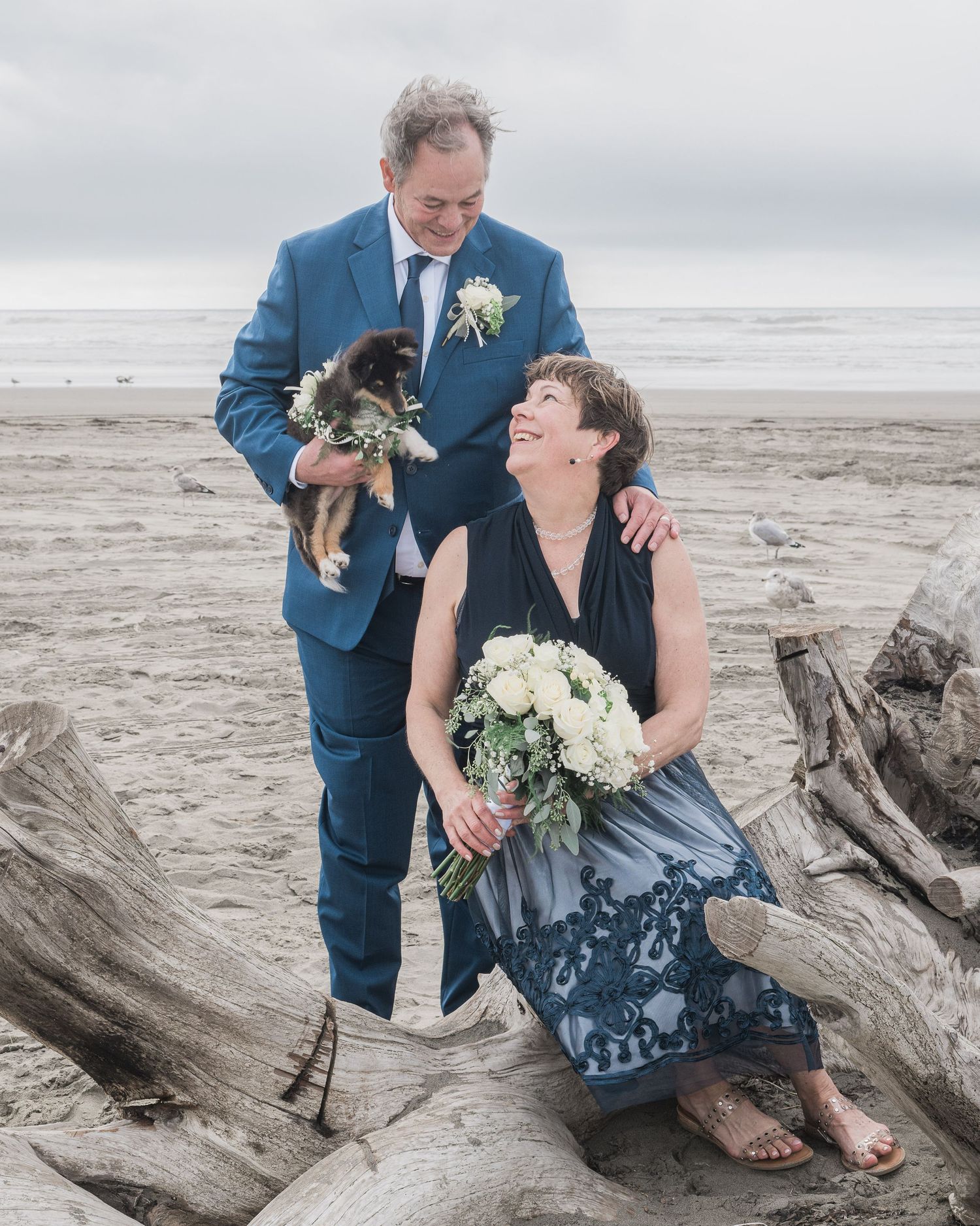Romantic couple photos on driftwood at a misty beach wedding.