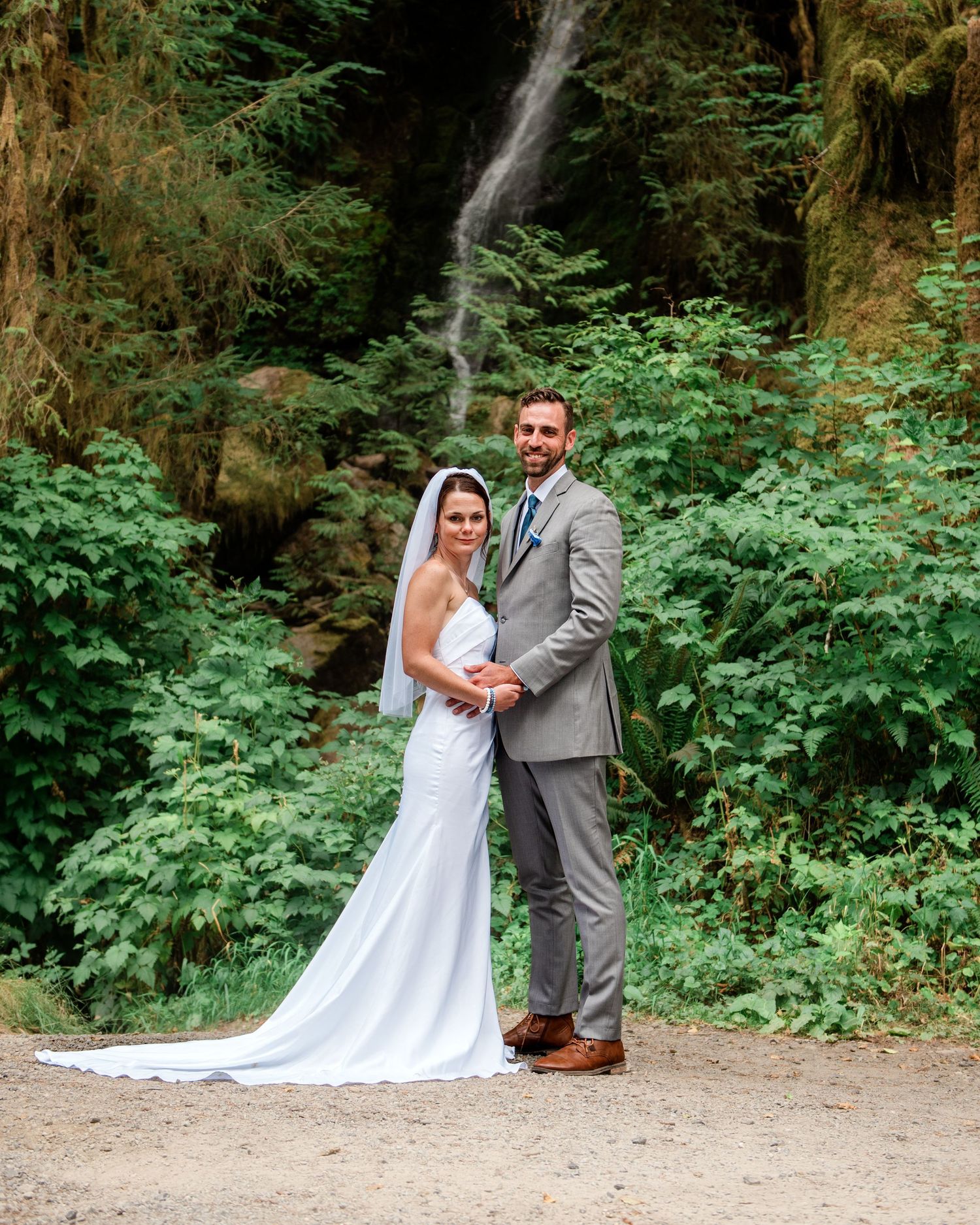 A couple poses together in a wooded outdoor setting during their wedding photo session.