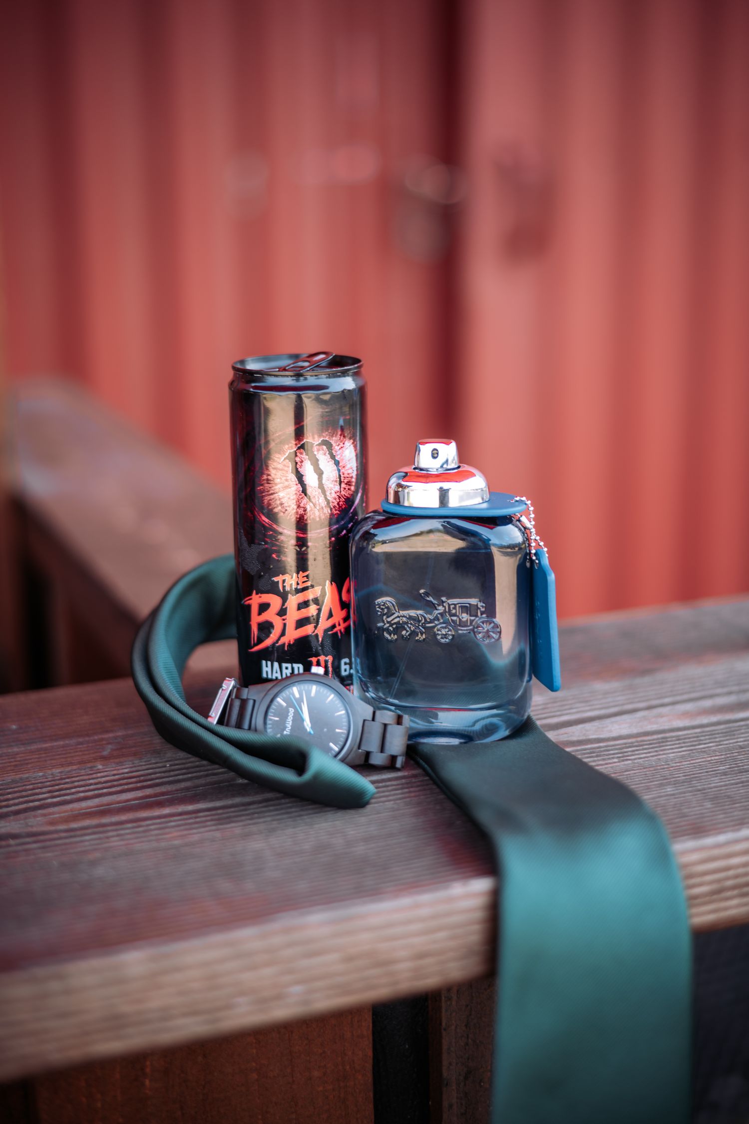 Energy drink and wireless earbuds arranged on wooden surface against red background.