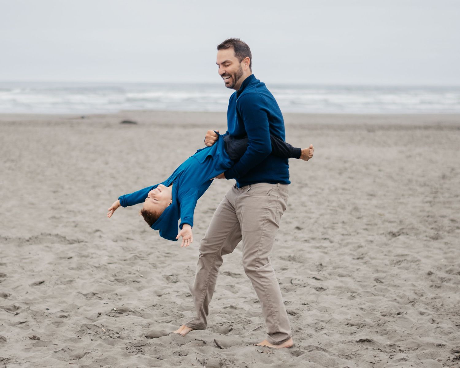 A playful moment of spinning and dancing on a cloudy beach.