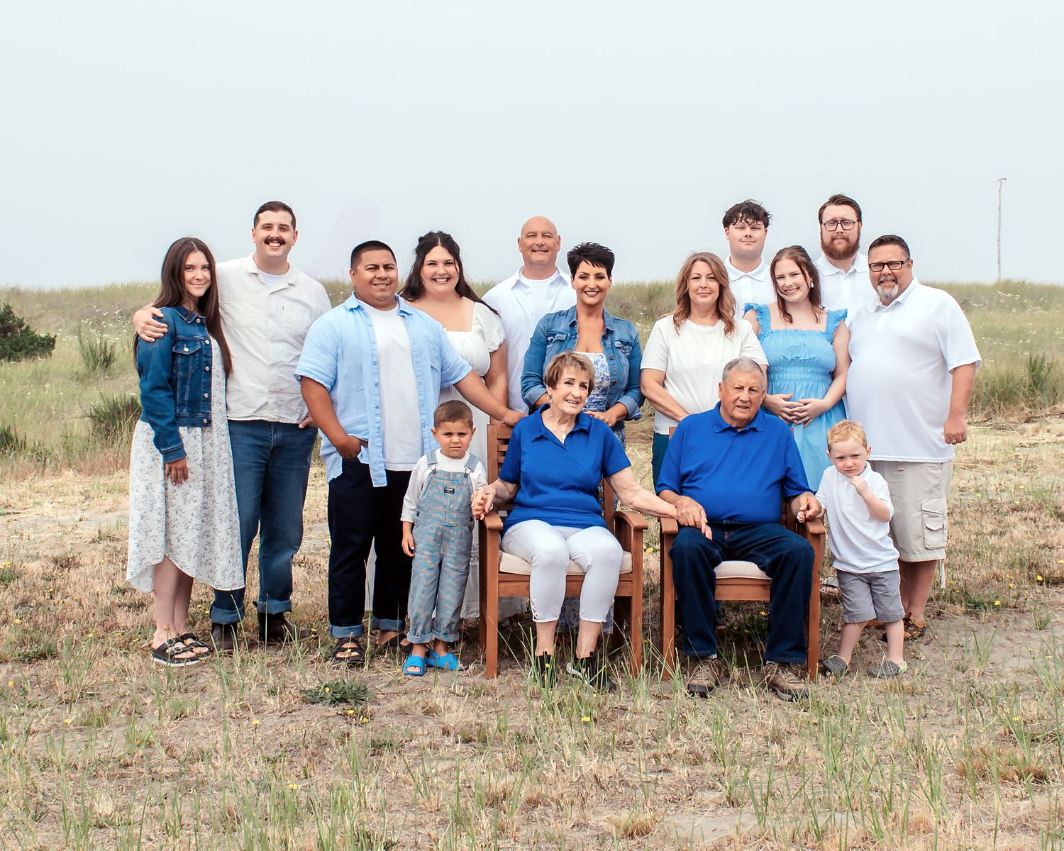 Large family group portrait outdoors in a field, with adults and children posing together for a formal photo.