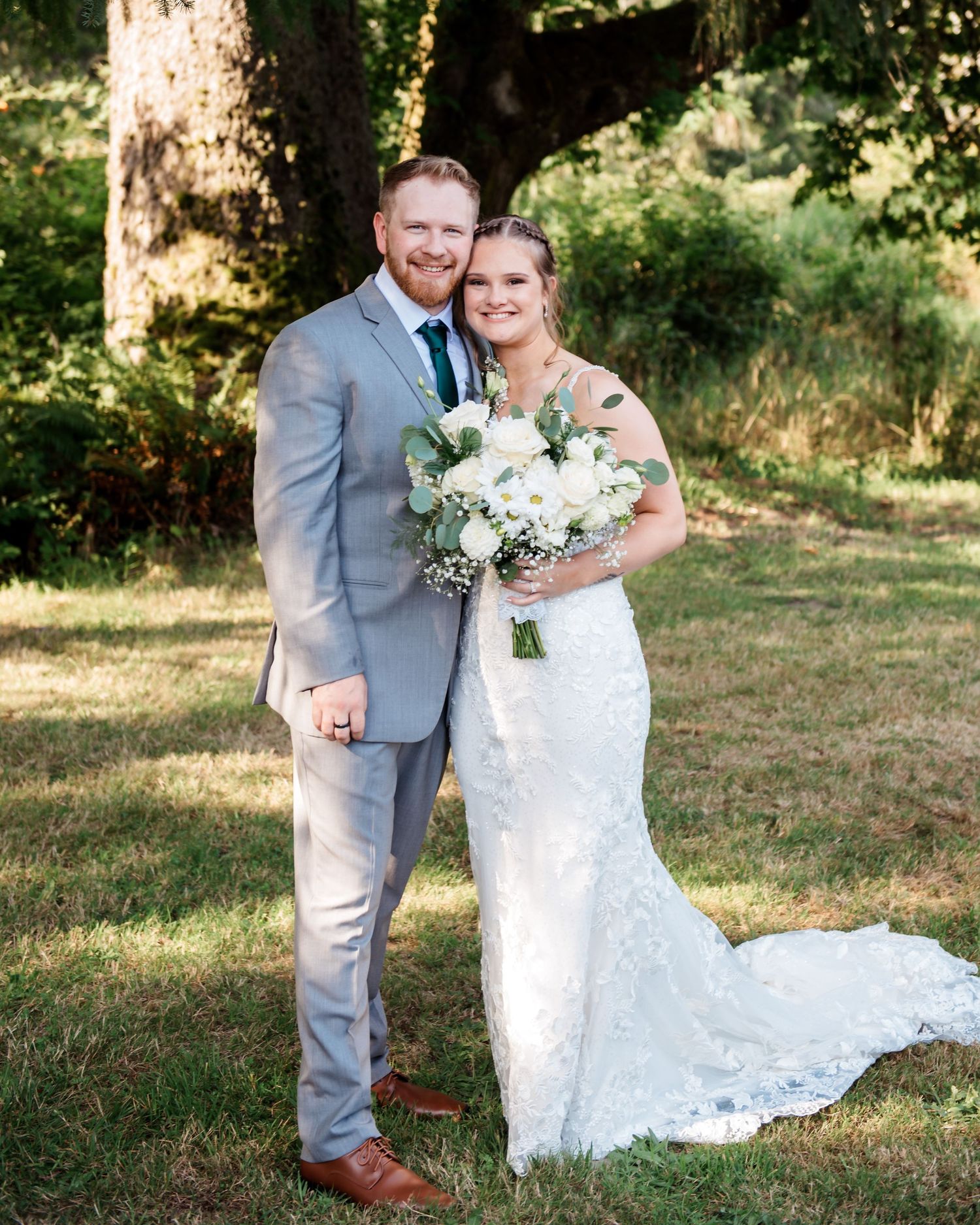 Newlyweds share tender moments in outdoor garden setting with lace wedding dress.