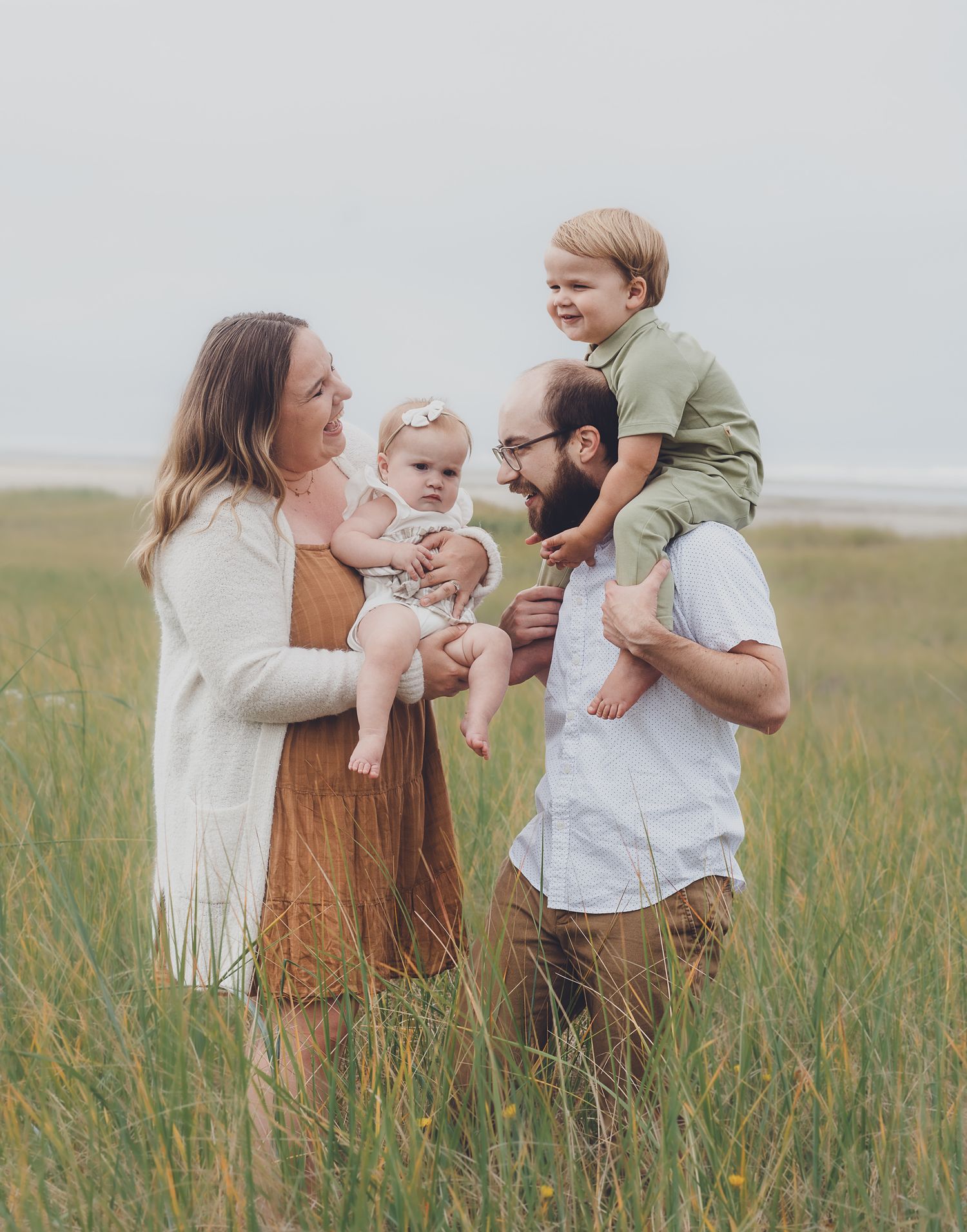 Family enjoying a tender moment together in a tall grass field.