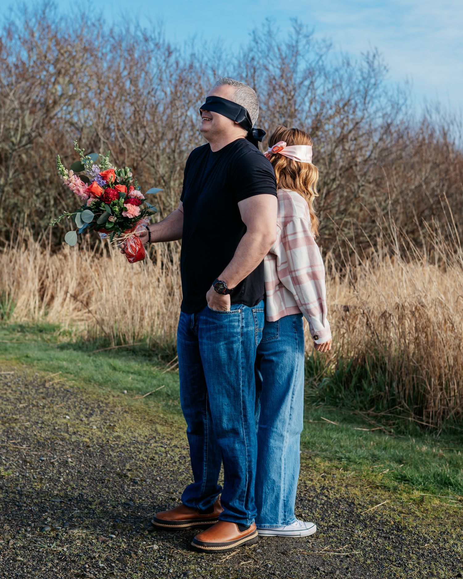 Couple in casual denim outfits sharing intimate moment during outdoor stranger/blind date photo session.