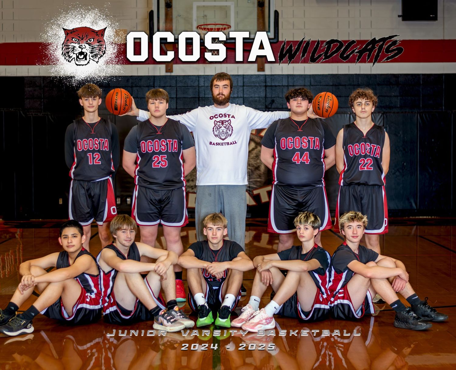 Youth basketball team poses in dark uniforms with their coach for team photo in gymnasium.