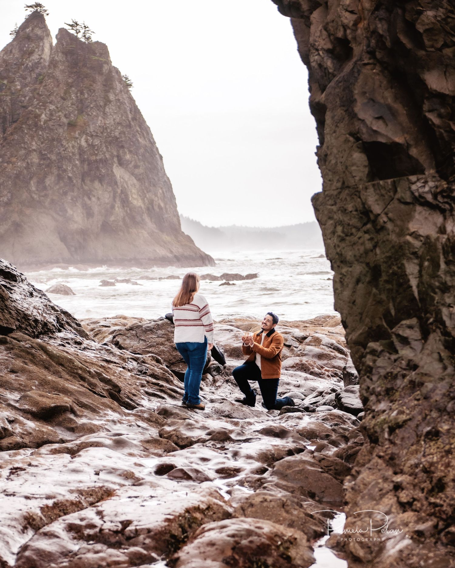 A proposal moment captured between rocky coastal formations at the beach.
