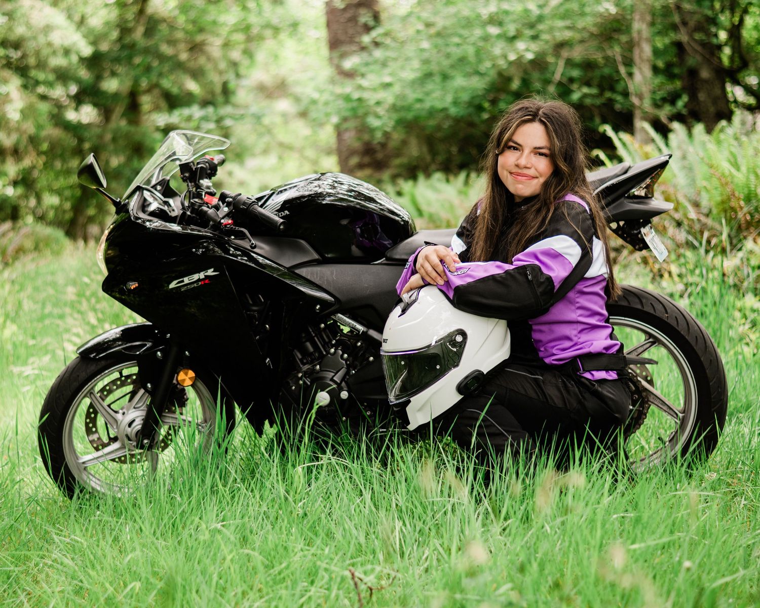 A black motorcycle parked in tall grass during an outdoor photo session.