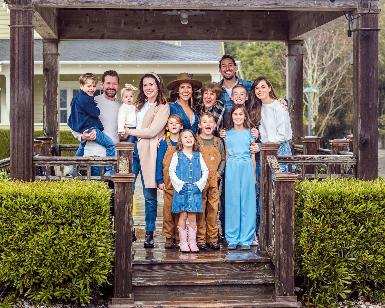 Extended family gathering under wooden pergola for outdoor portrait session.