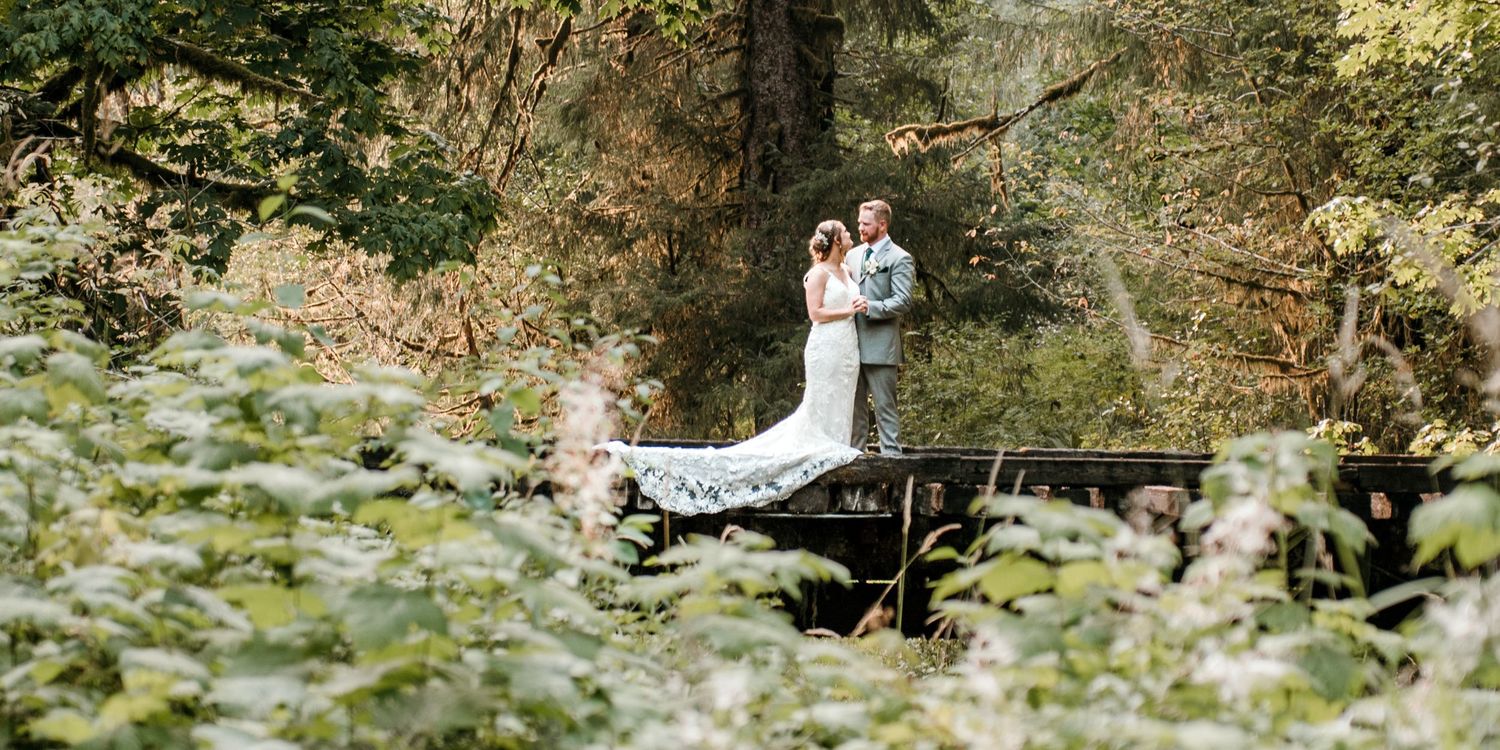 Wedding couple poses playfully in lush garden setting with natural greenery.