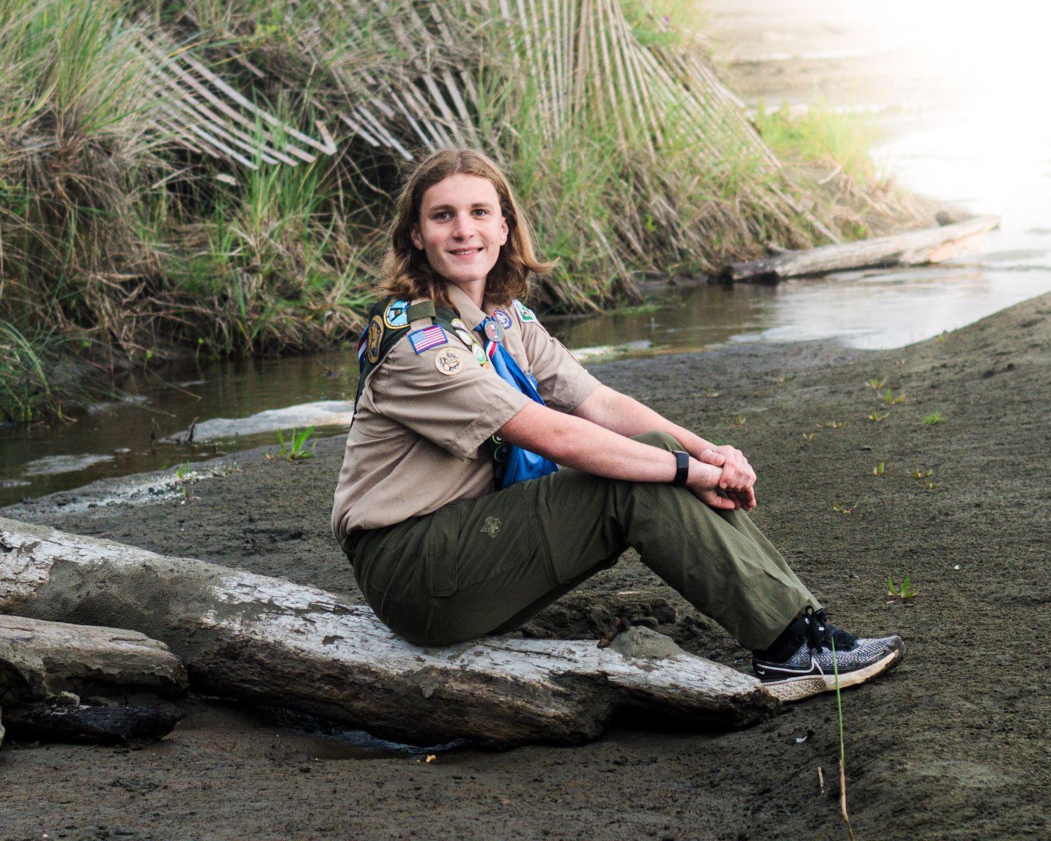 A relaxed outdoor portrait session by a flowing stream with natural rocks and vegetation.