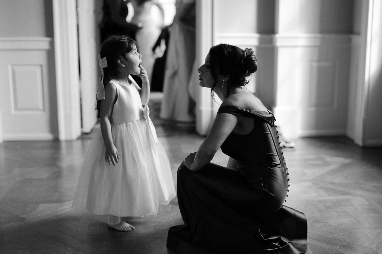 A black and white photograph shows an elegant moment between two figures in formal attire on a polished floor.