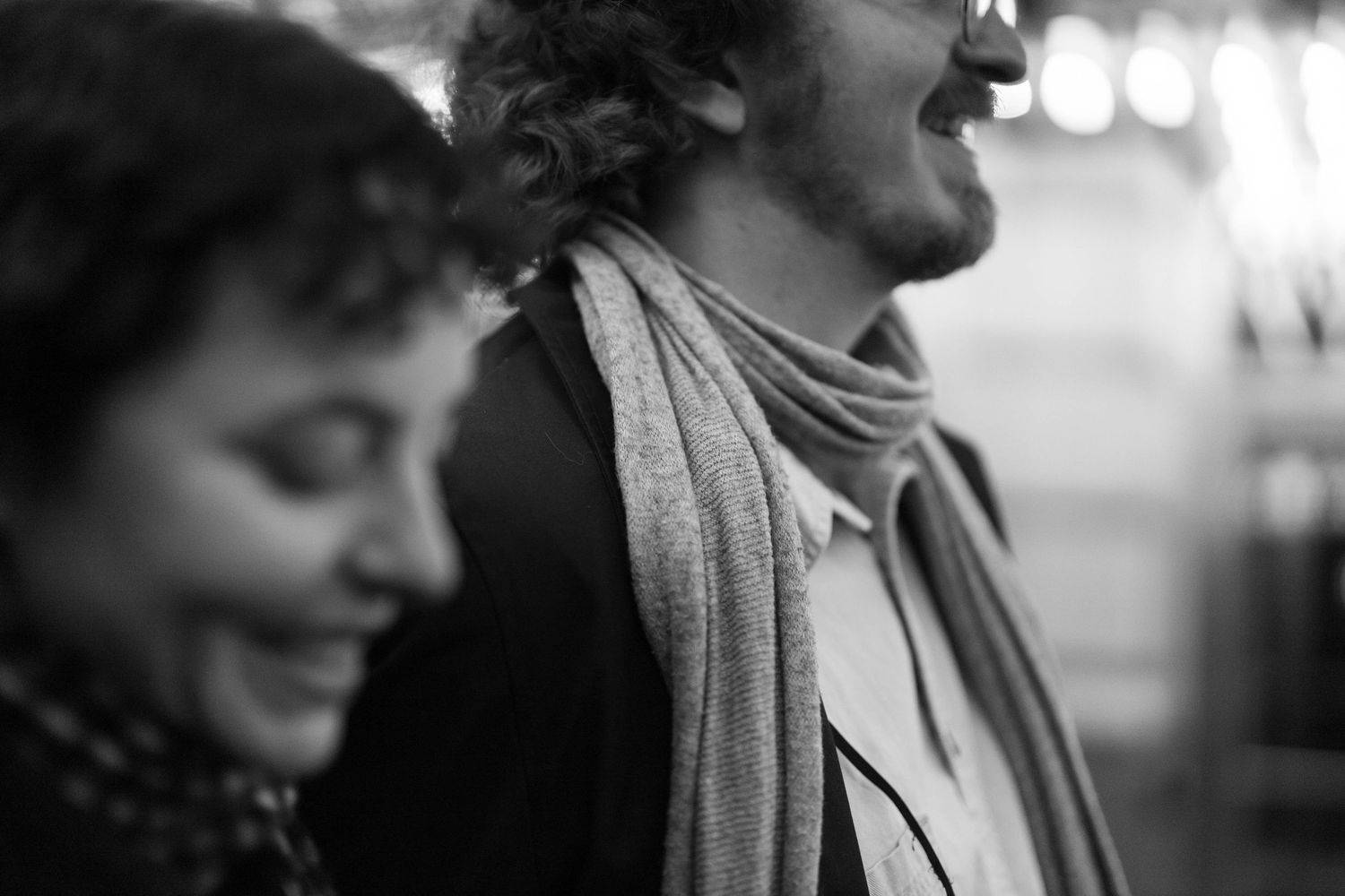 Black and white photo of a smiling woman and man with a scarf, captured in a candid moment.