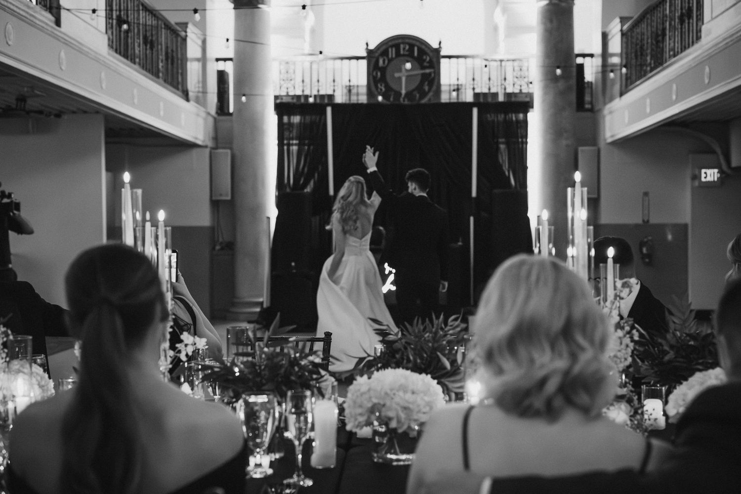 Bride and groom share a first dance in a candlelit black and white wedding reception hall.