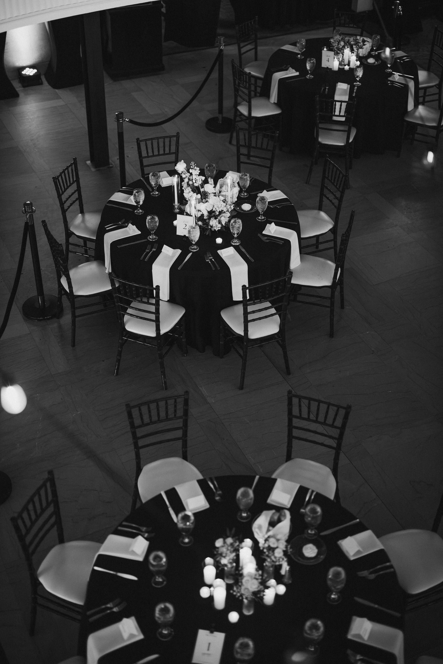 Black and white aerial view of round reception tables with candles and floral centerpieces.